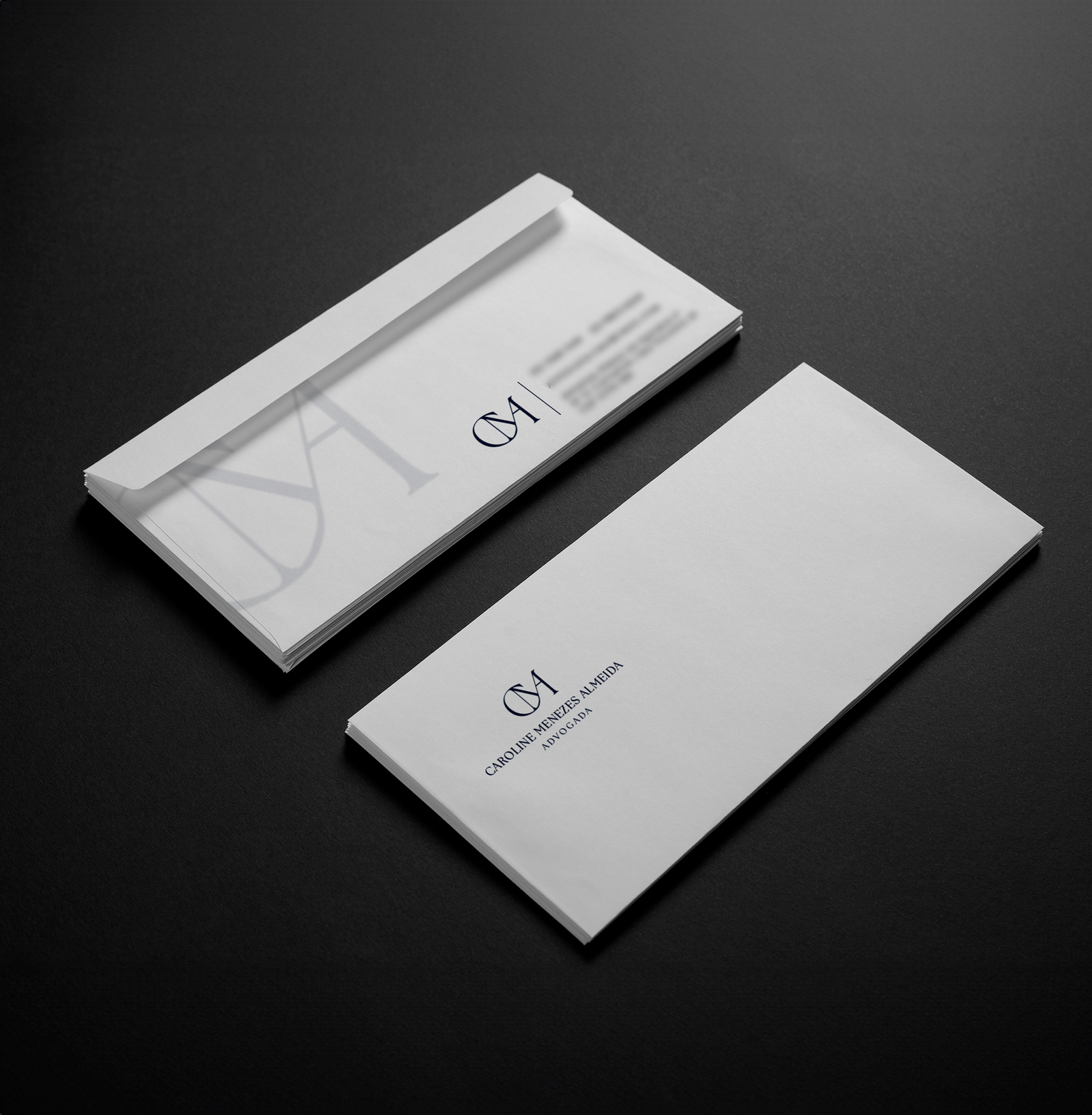 Envelopes brancos personalizados com o logotipo minimalista “CMA” impresso em azul-marinho, representando a identidade visual da advogada Caroline Menezes Almeida. O design é elegante e profissional, disposto sobre fundo preto, transmitindo sofisticação e autoridade jurídica.