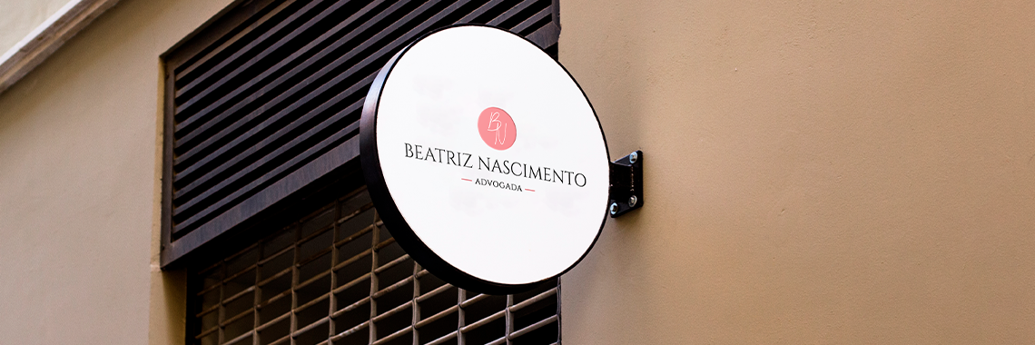 Placa redonda com logotipo de escritório jurídico em fachada moderna, representando identidade visual criada pela Jurinow.