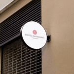 Placa redonda com logotipo de escritório jurídico em fachada moderna, representando identidade visual criada pela Jurinow.